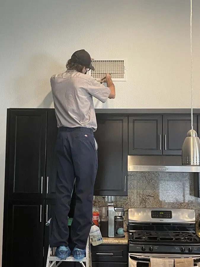 Technician inspecting an air vent during HVAC service in Redondo Beach